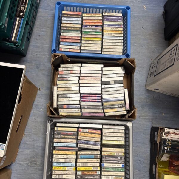 Mixed cassette tape lot in plastic storage boxes.