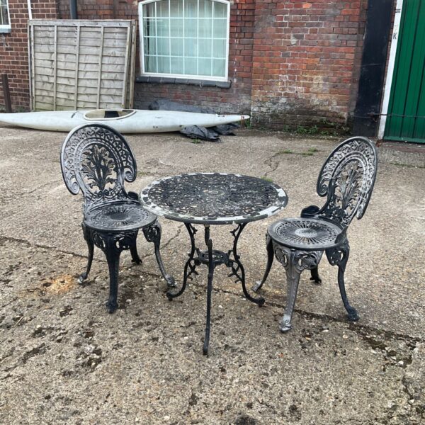 Vintage cast iron garden table and chairs in a garden setting.