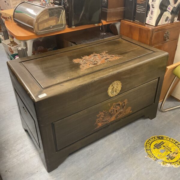 Front view of a vintage Chinese camphor wood chest with engravings.