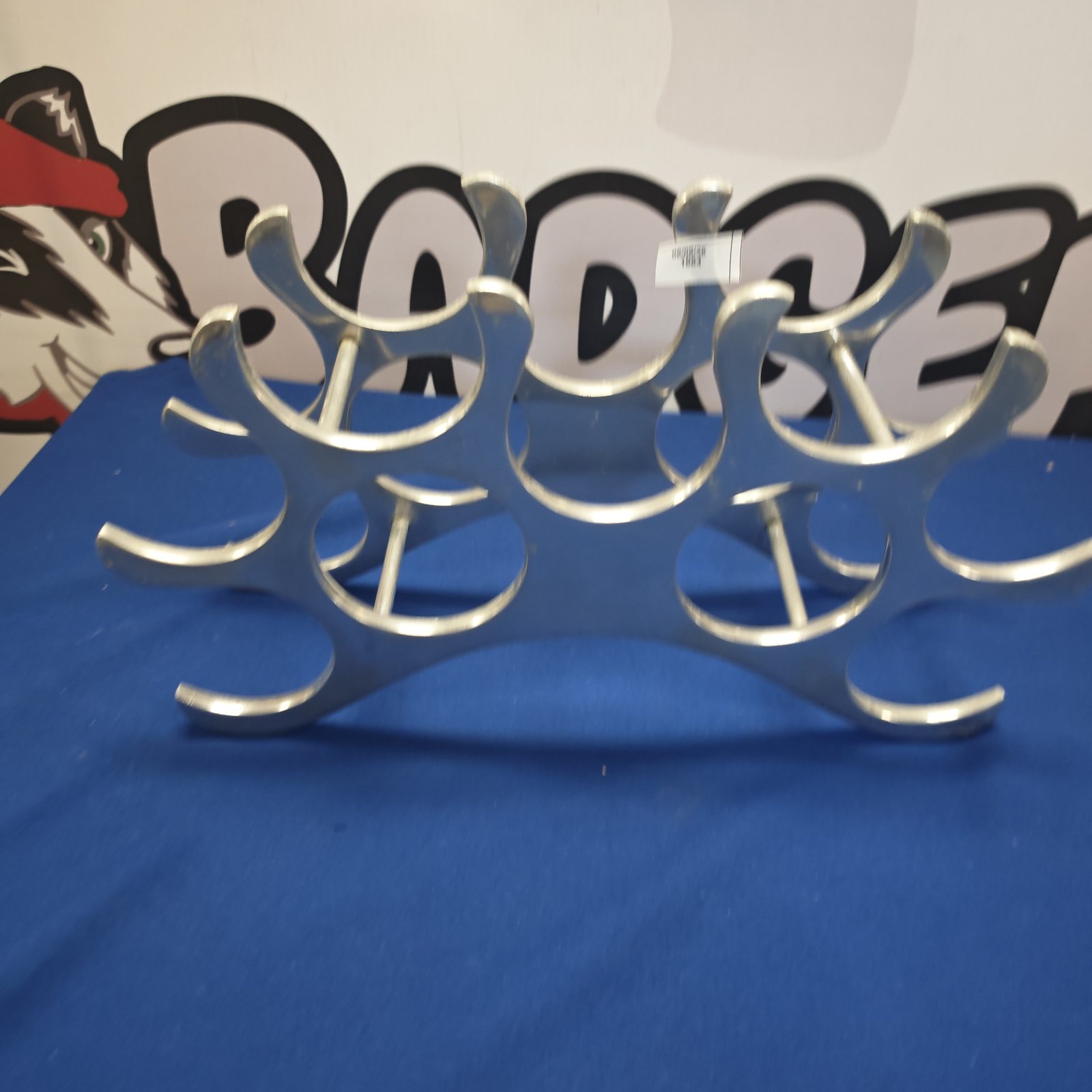 Polished chrome wine bottle holder with curved arms for display.