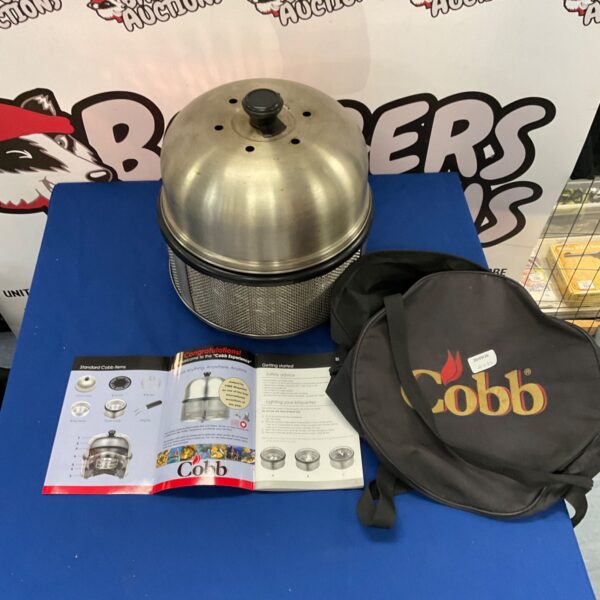 Stainless steel Cobb portable grill with black carry case.