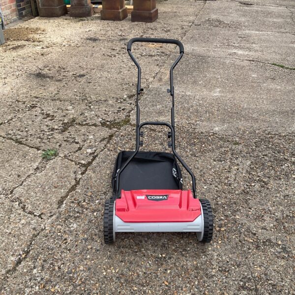 Used Cobra push lawn mower in a garden setting.