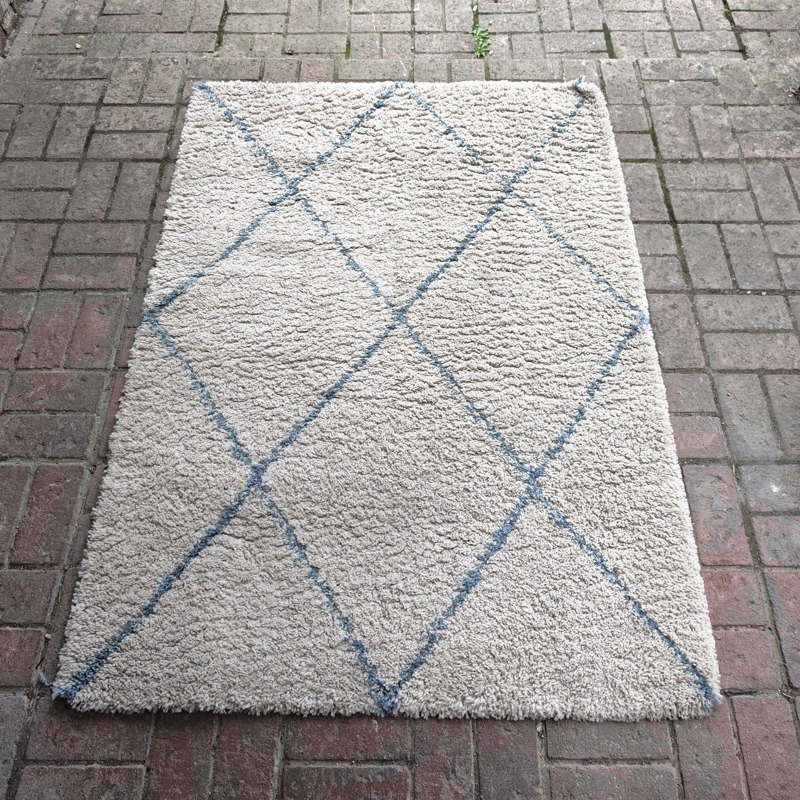 Cream shag pile rug with geometric pattern, approximately 4ft x 5ft.