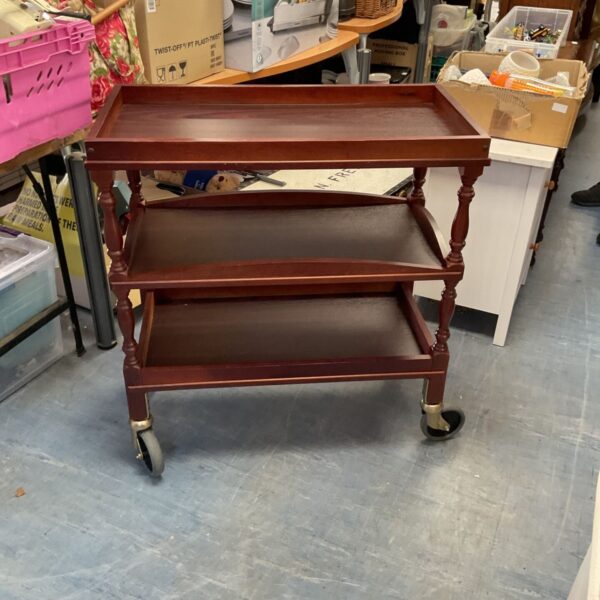 Dark wood three tier trolley with castors for easy movement.