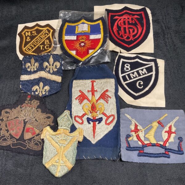 Collection of vintage embroidered badges including military and university insignia.