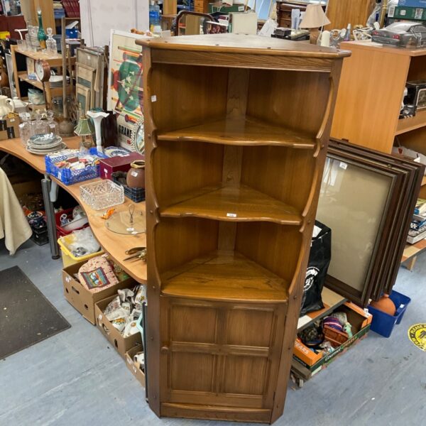 Vintage Ercol teak corner unit in a cluttered antique shop.