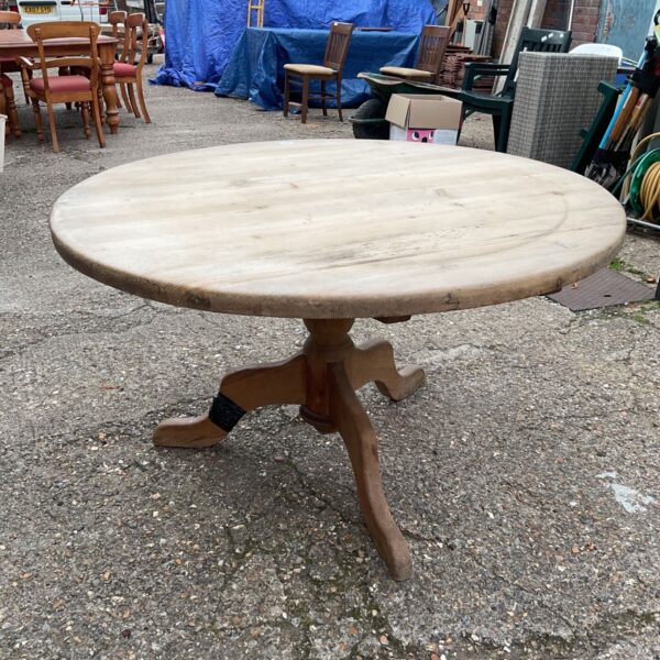 Vintage farmhouse kitchen table with a round pine top.