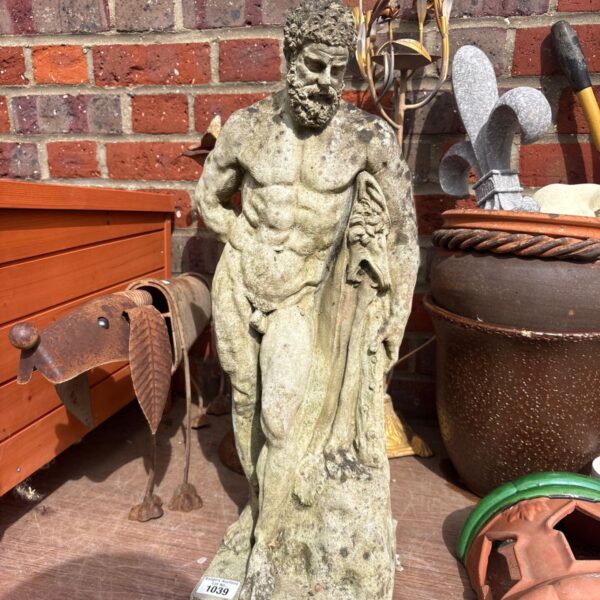 Stone garden statue of the Farnese Hercules in a garden setting.