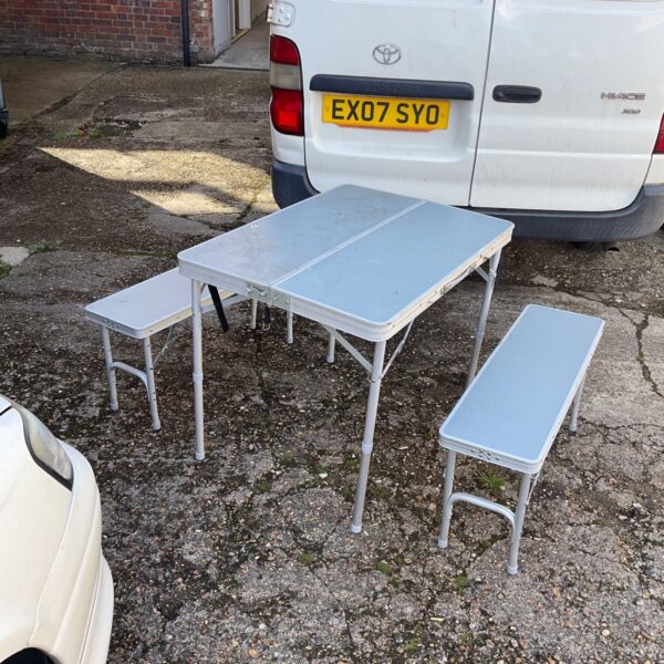 Folding picnic set with table and benches in a garden setting.