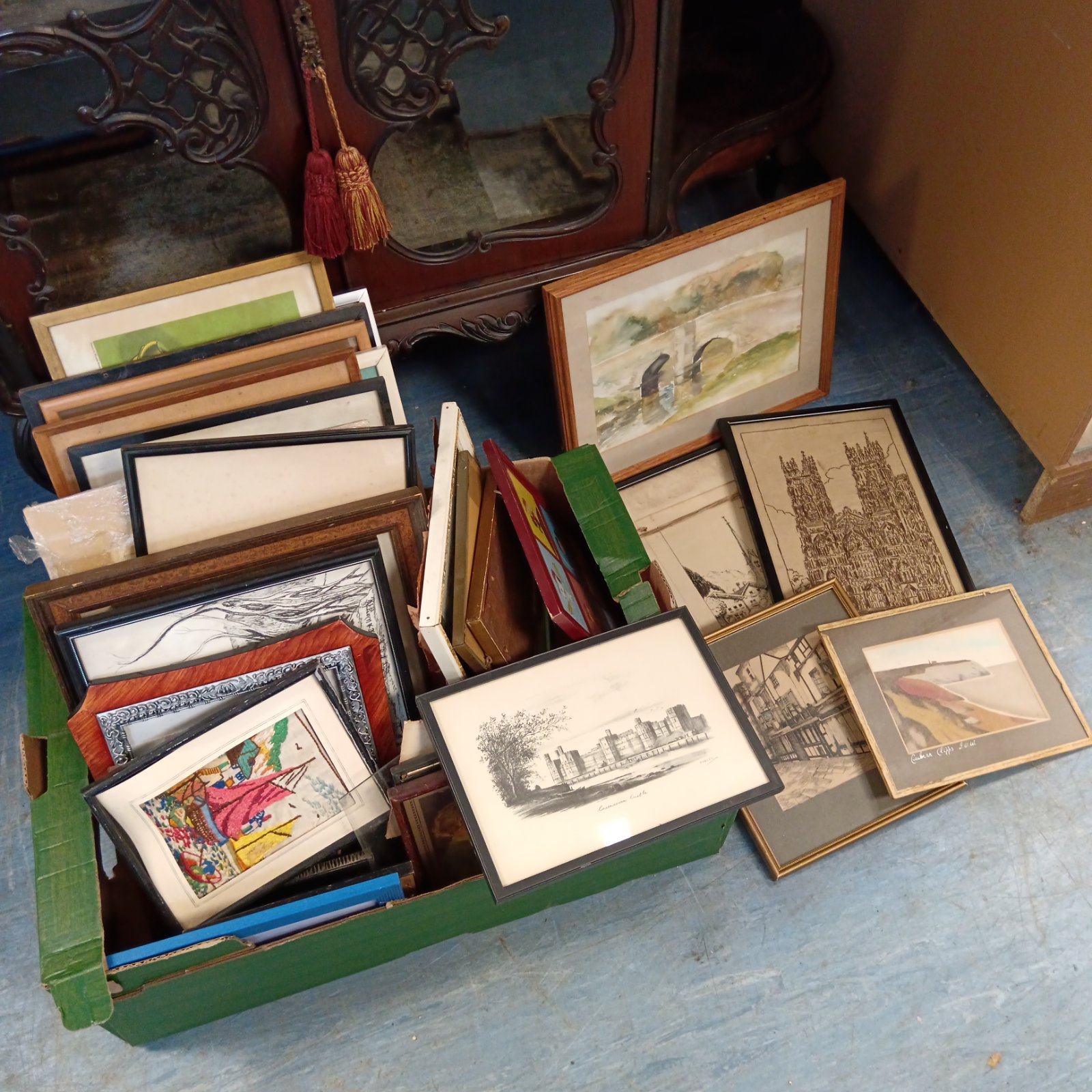 Large collection of framed prints and original artworks in a box.