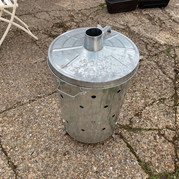 Galvanised incinerator for burning garden waste outdoors.