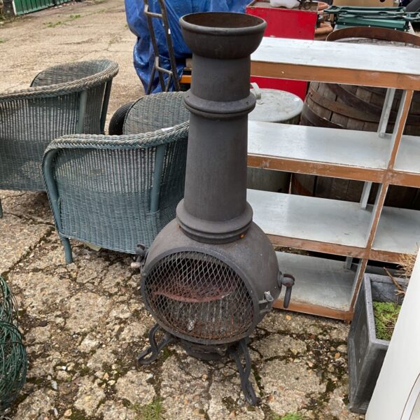 Weathered cast iron garden chiminea in a garden setting.