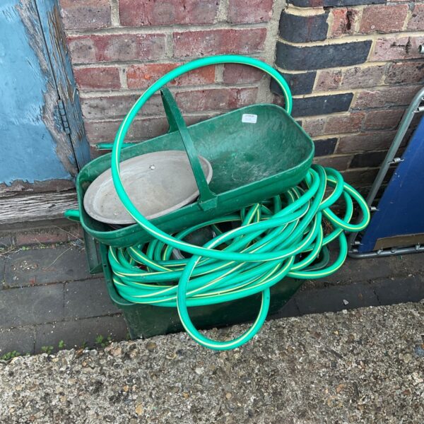 Green garden hose neatly coiled inside a green storage box.