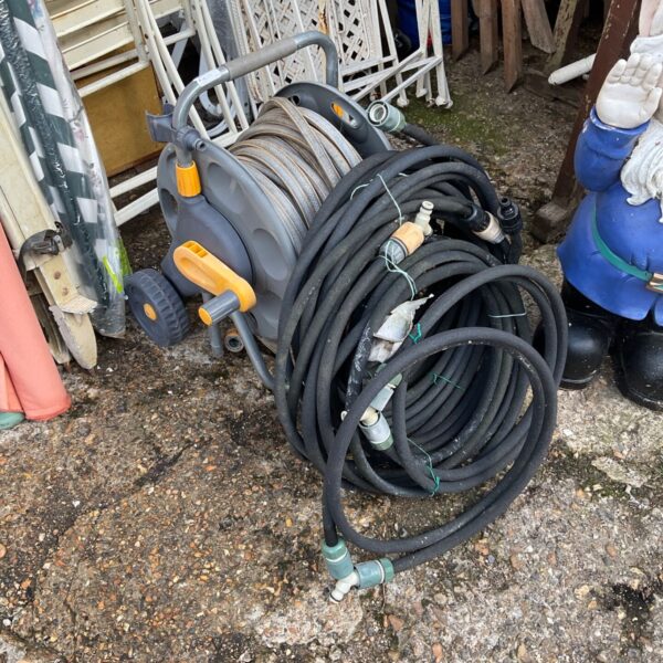 Black garden hose reel with yellow handle for outdoor watering.