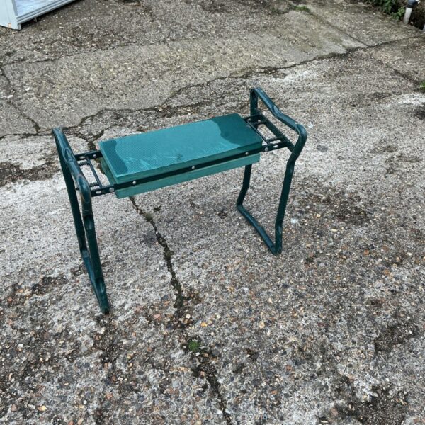 Green metal garden planter stool with folding legs.