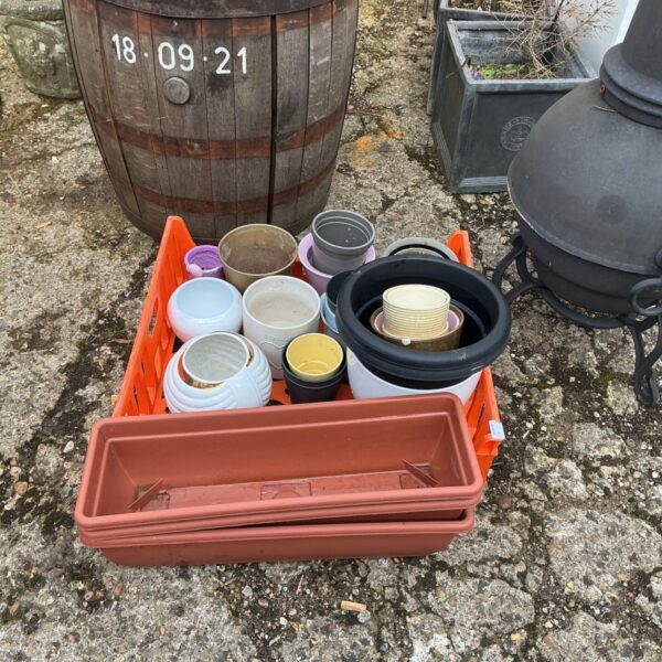 Assorted terracotta and ceramic garden pots and troughs in a garden setting.