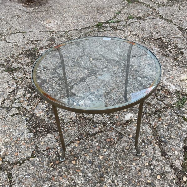Vintage garden table with a glass top and metal legs.