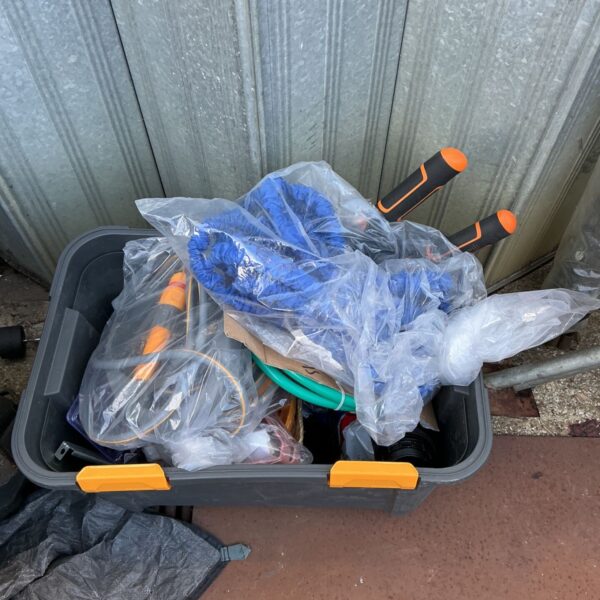 Garden tool lot with coiled hosepipe in a storage box.