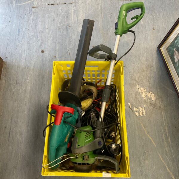 Crate of assorted garden tools including a hedge trimmer and leaf blower.