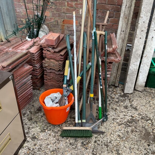 Selection of used garden tools including clippers in a bucket.