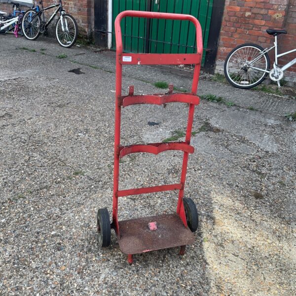 Vintage gas cylinder trolley with steel frame and four wheels.