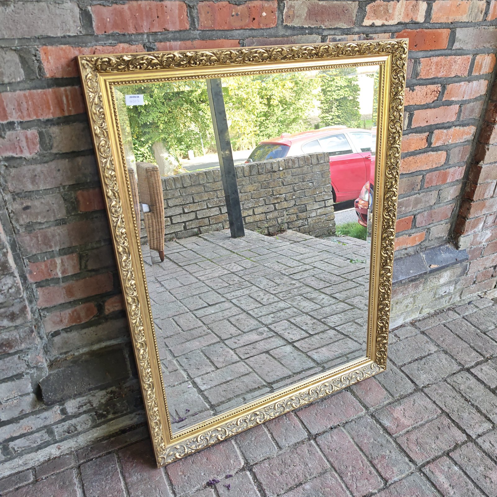 Large gilt framed mirror with ornate detailing.
