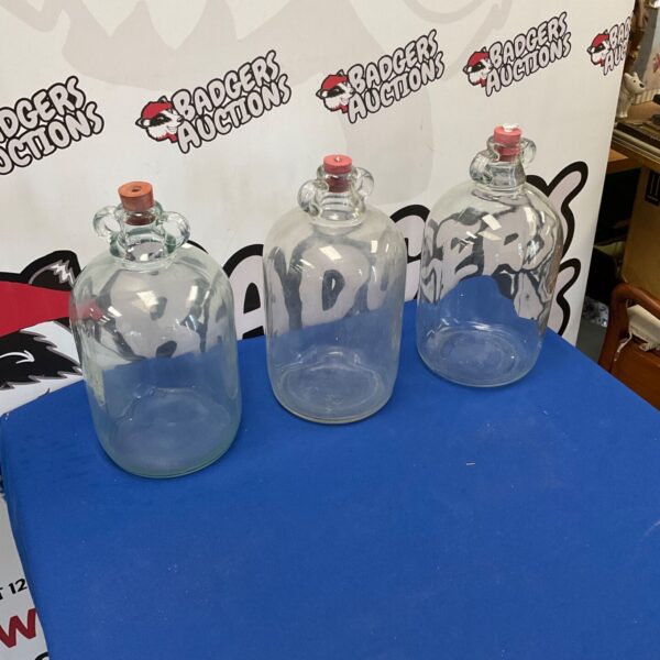 Lot of three vintage glass demijohns for storage.