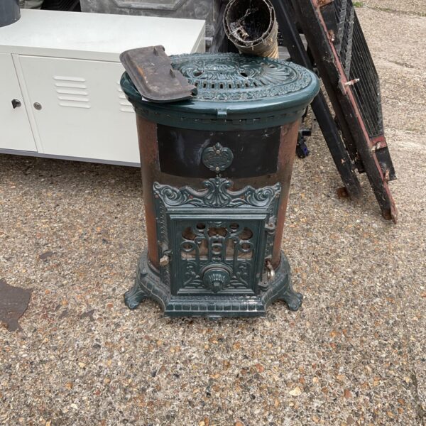 Antique Godin wood burning stove with flue, showing intricate detailing.