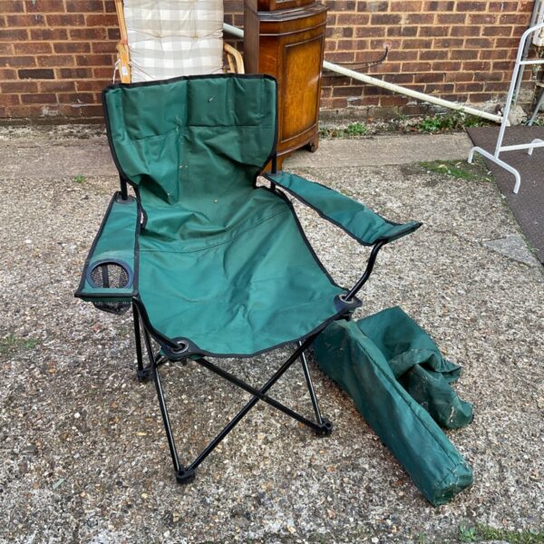 Green folding camping chair with carry bag, ideal for outdoor use.