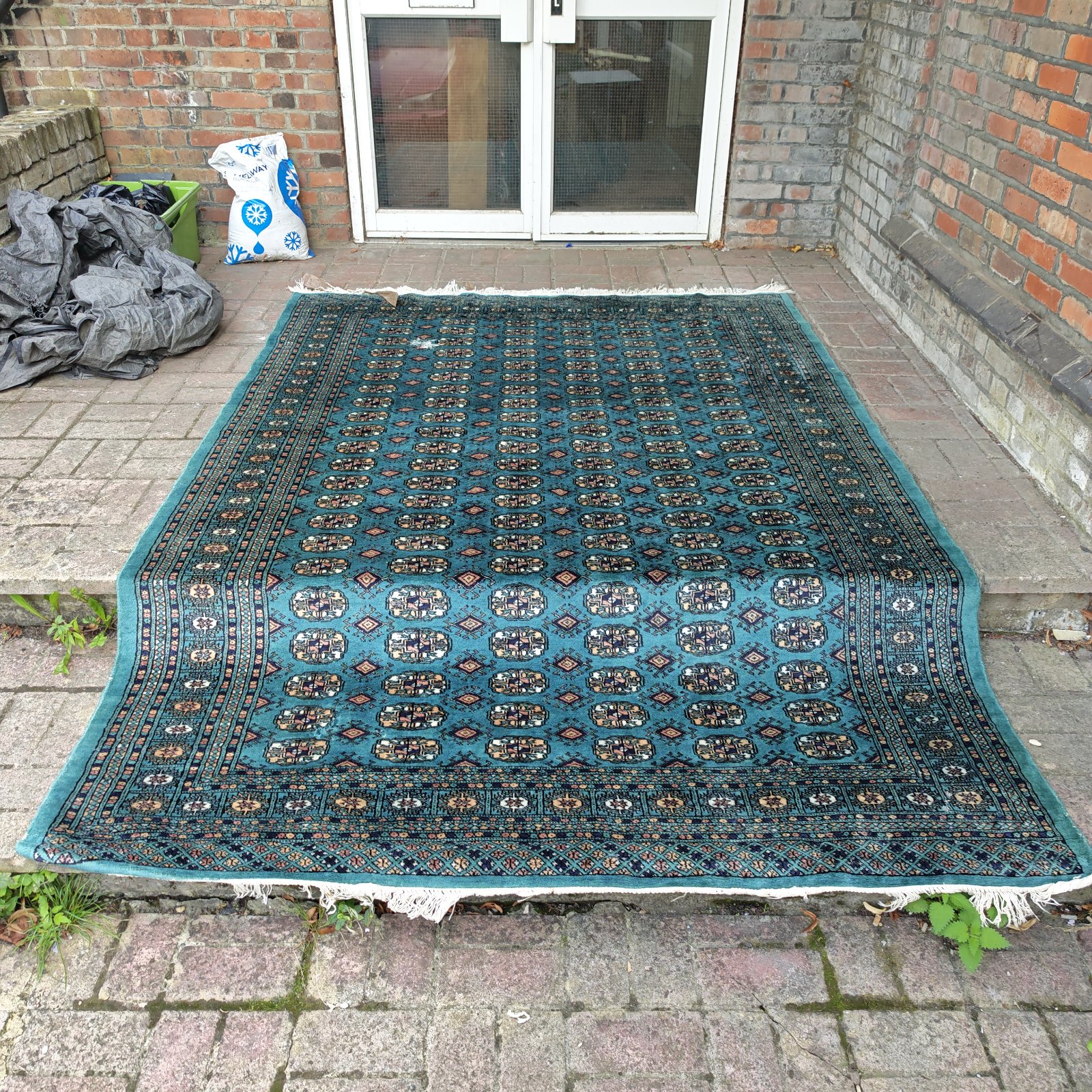 Large green geometric pattern rug displayed outdoors.