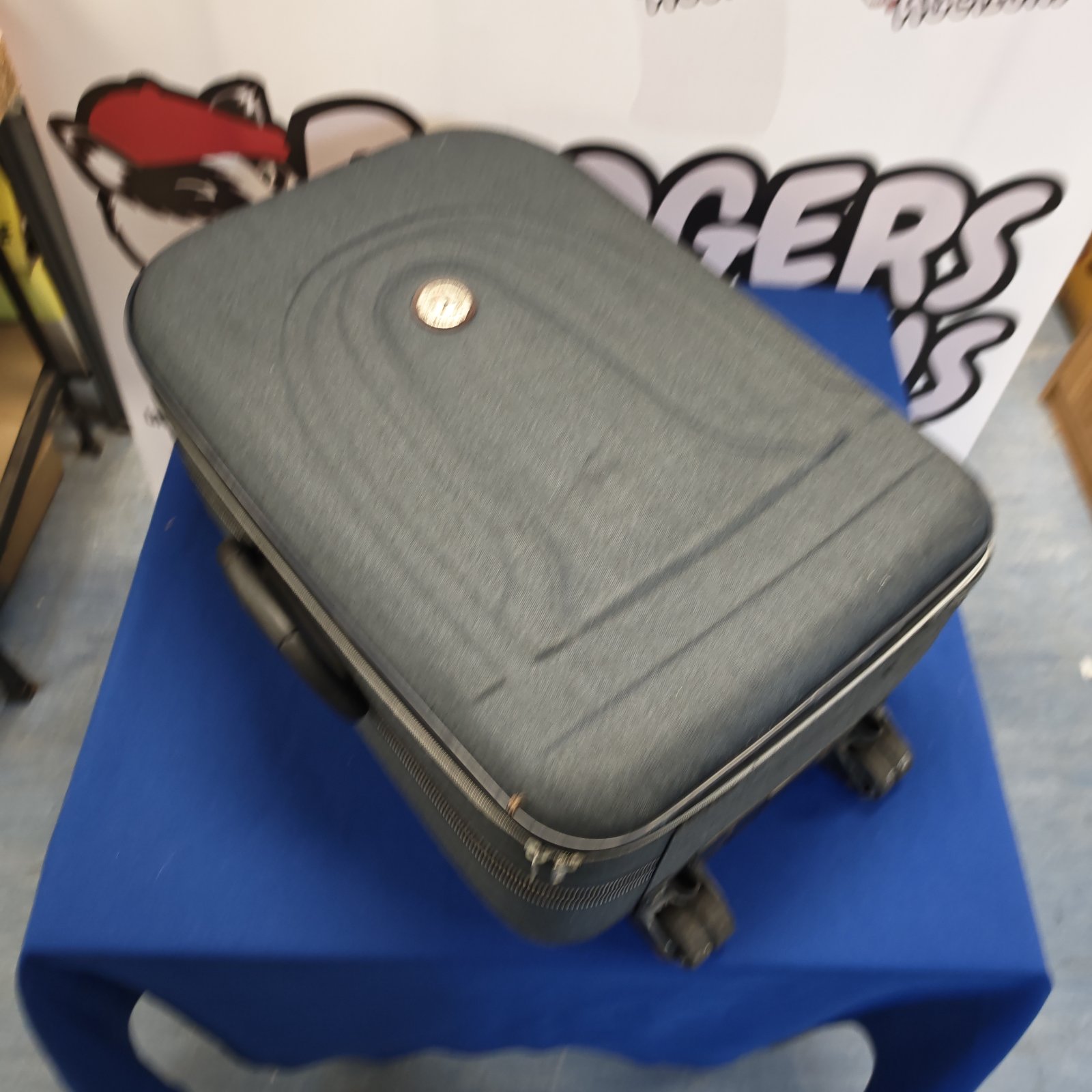 Grey wheeled suitcase with extendable handle and casters for travel.
