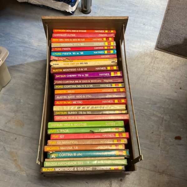 Stack of vintage Haynes manuals for car repair and maintenance.