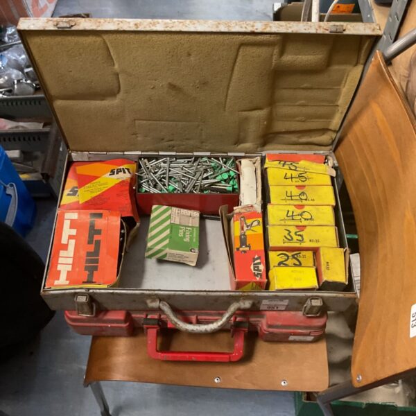 Open red toolbox containing a Hilti nail gun and nails.