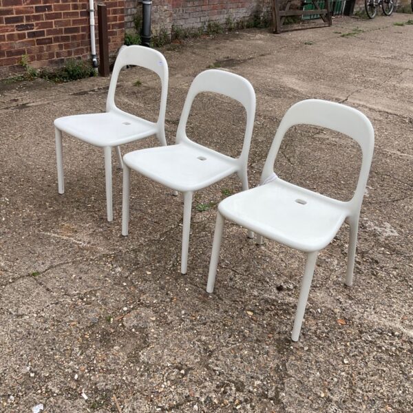Lot of three vintage Ikea plastic chairs in a garden setting.
