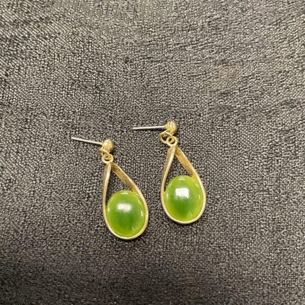 Close-up of vintage jade teardrop earrings with gold settings.