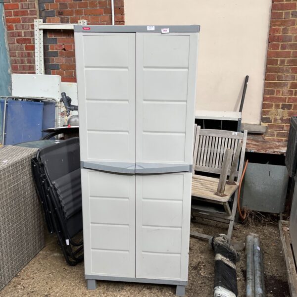 Grey Keter garden storage cabinet with two doors, showing signs of weathering.
