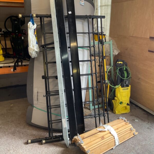 Dismantled king size metal bed frame with wooden slats.