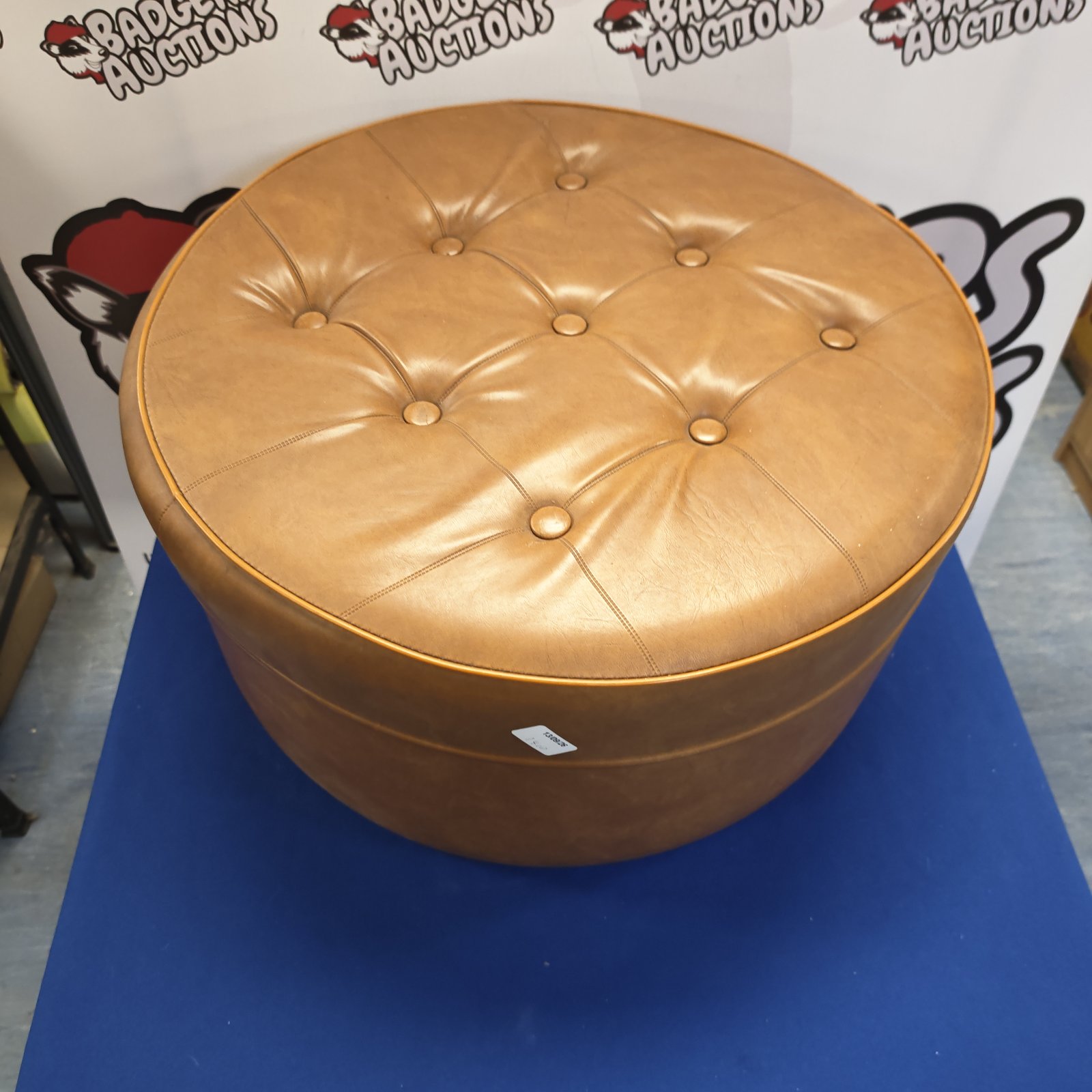 Light brown leather pouffe with button detailing, vintage style.