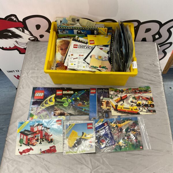 Box of assorted Lego set instructions manuals for building.