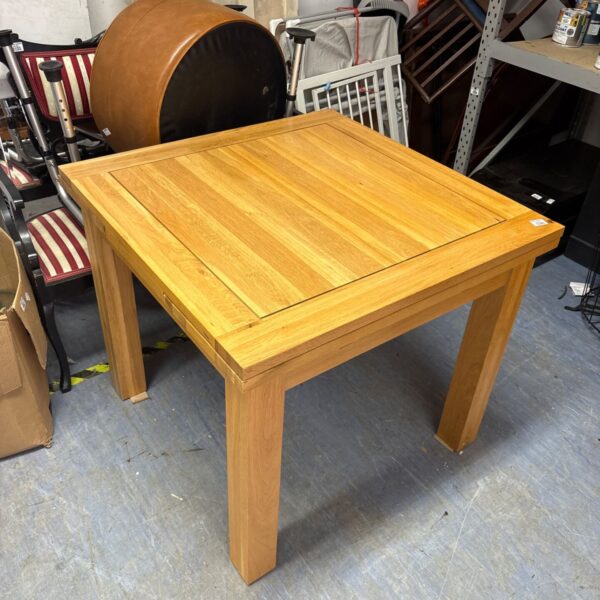 Light oak square extending dining table in a room setting.