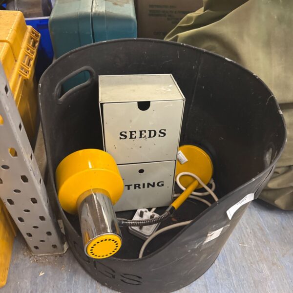Metal log bucket filled with a lamp, seeds and a drawer.