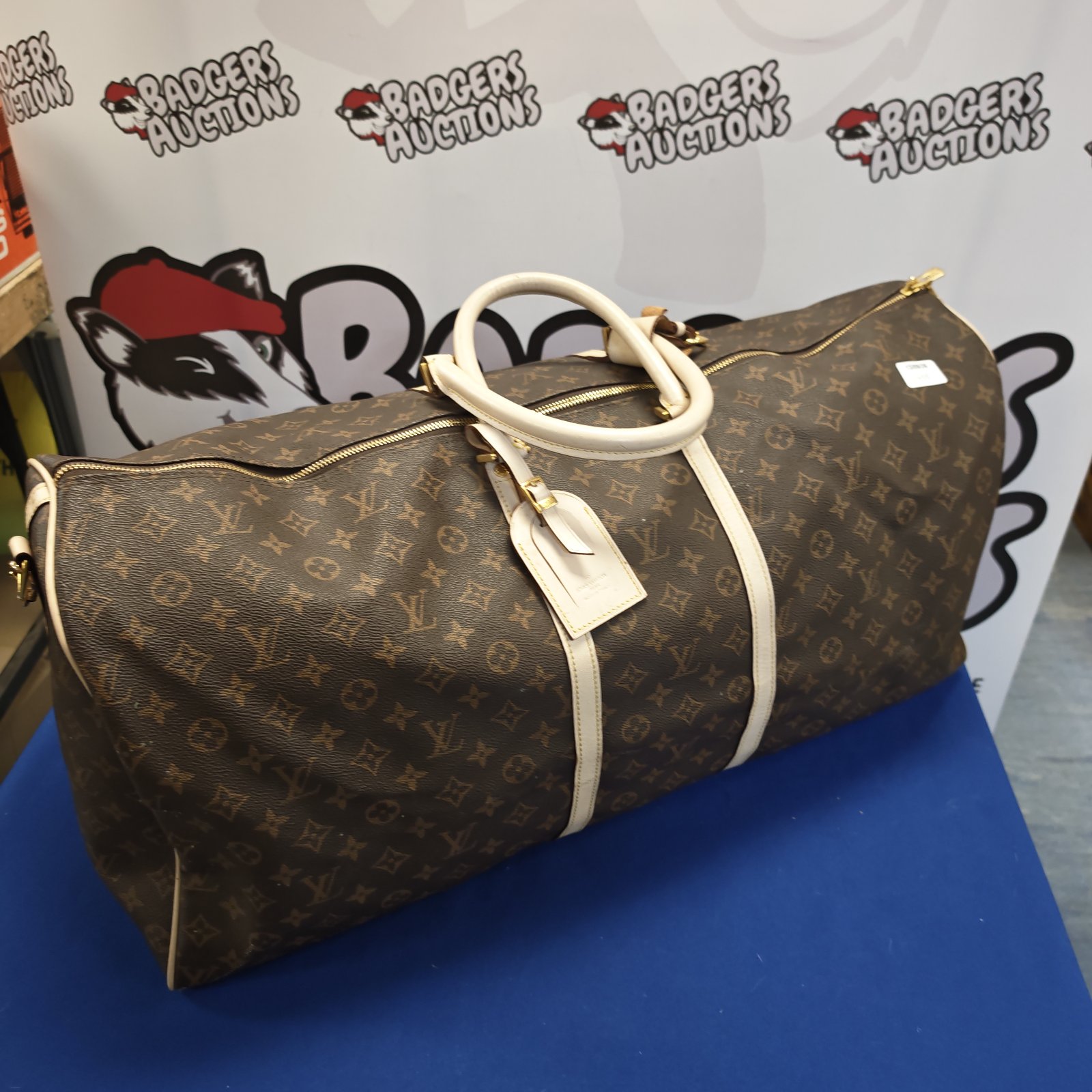 Brown Louis Vuitton style holdall with twin handles.