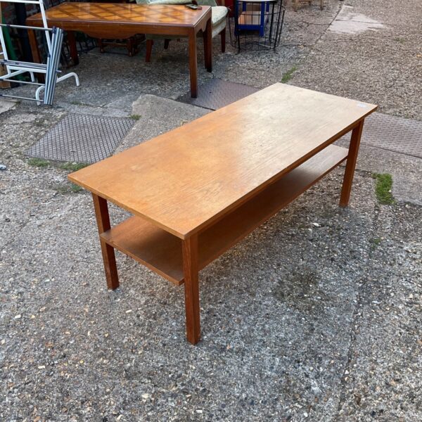 Vintage mahogany coffee table with lower shelf in a home setting.
