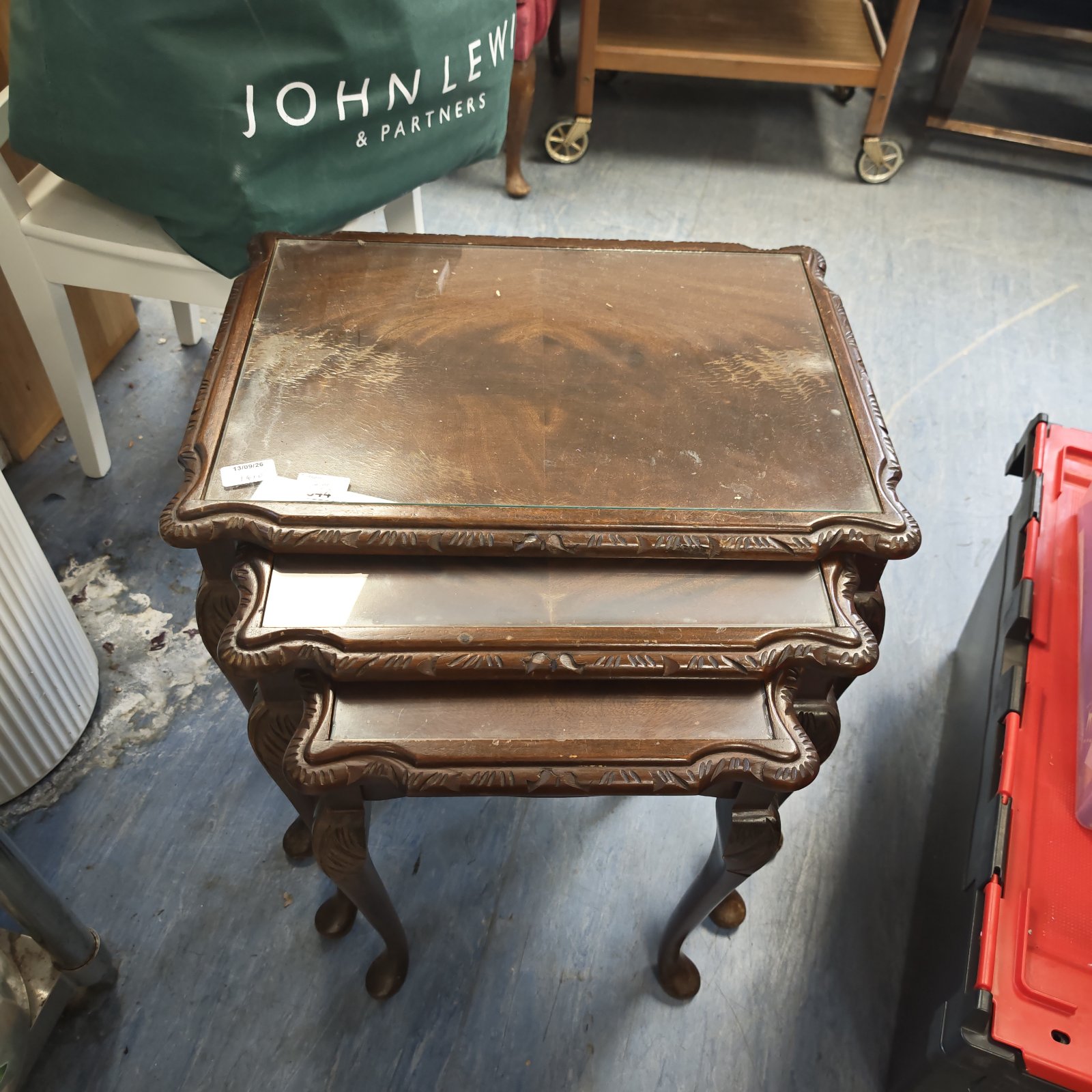 Antique mahogany nest of tables with glass tops and carved legs.