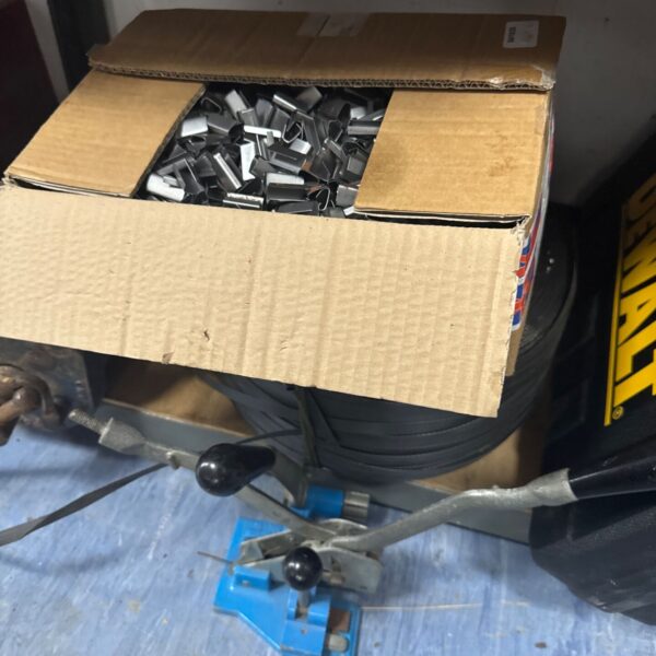 Metal banding kit with ratchet clamp and fasteners in a box.