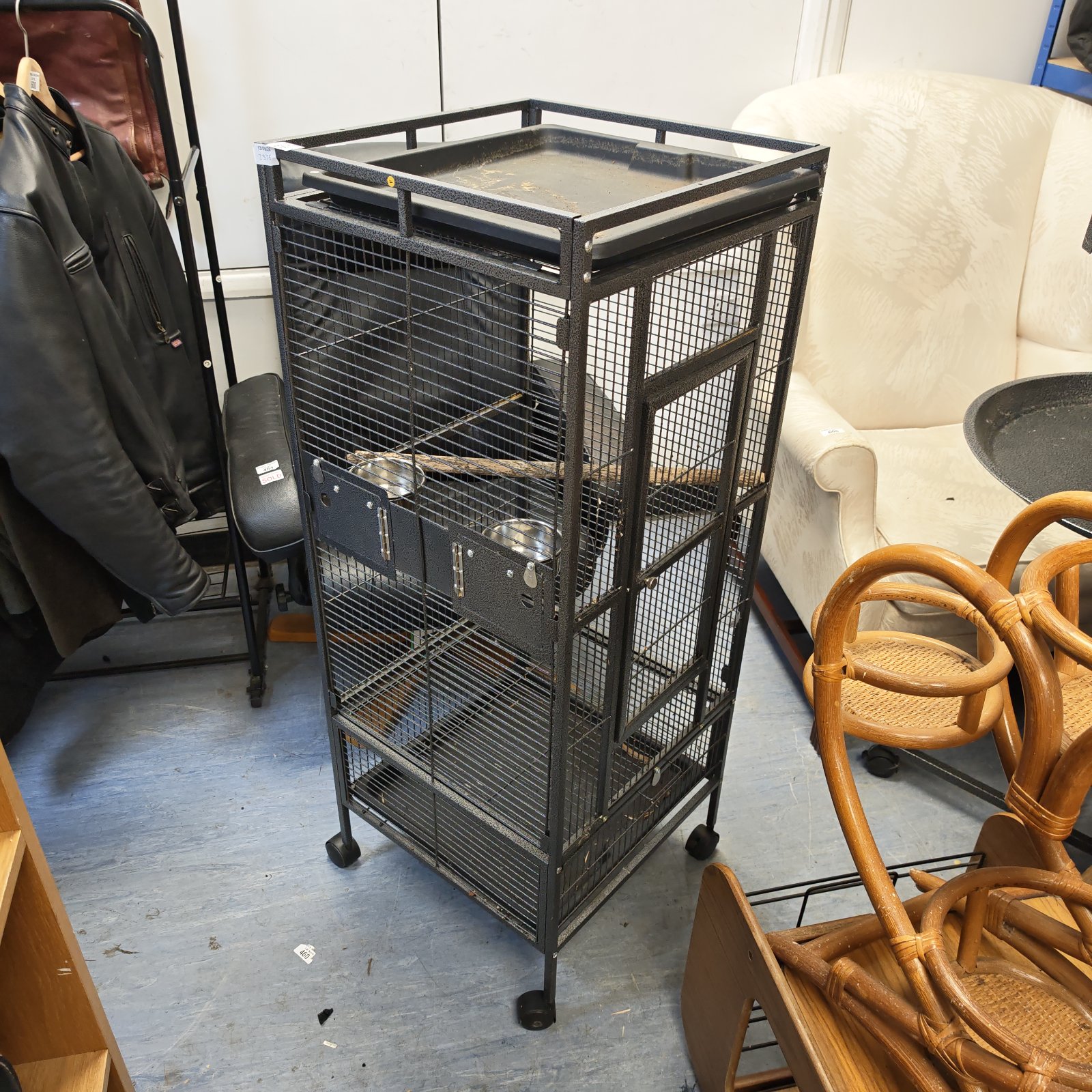 Tall metal bird cage on casters, ideal for pet birds.