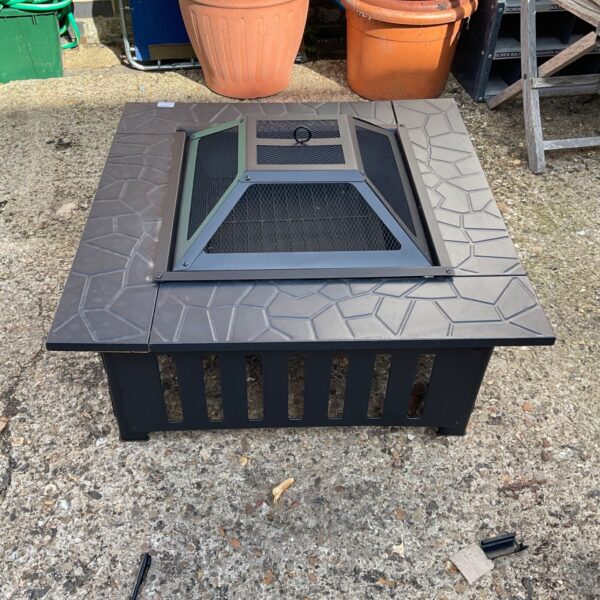 Dark metal fire pit in a garden setting.
