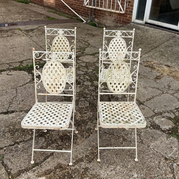 Vintage metal folding garden chairs with decorative backs.