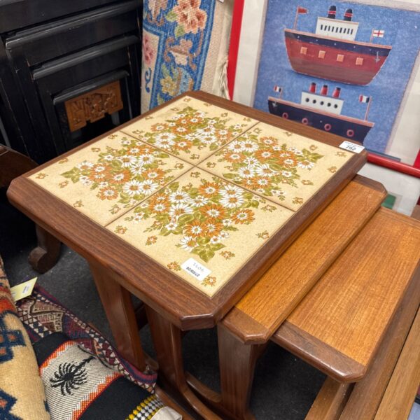Mid century nest of three tile top tables in warm wood tone.