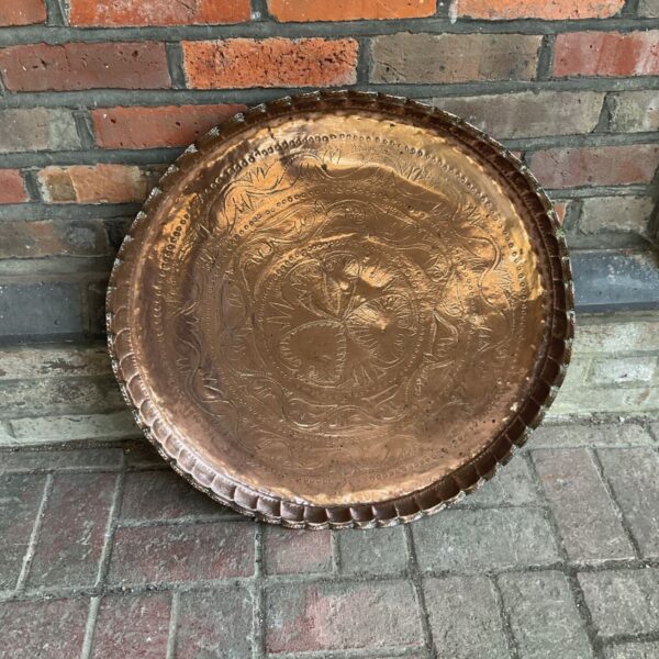Antique Middle Eastern copper charger with floral repoussé design.